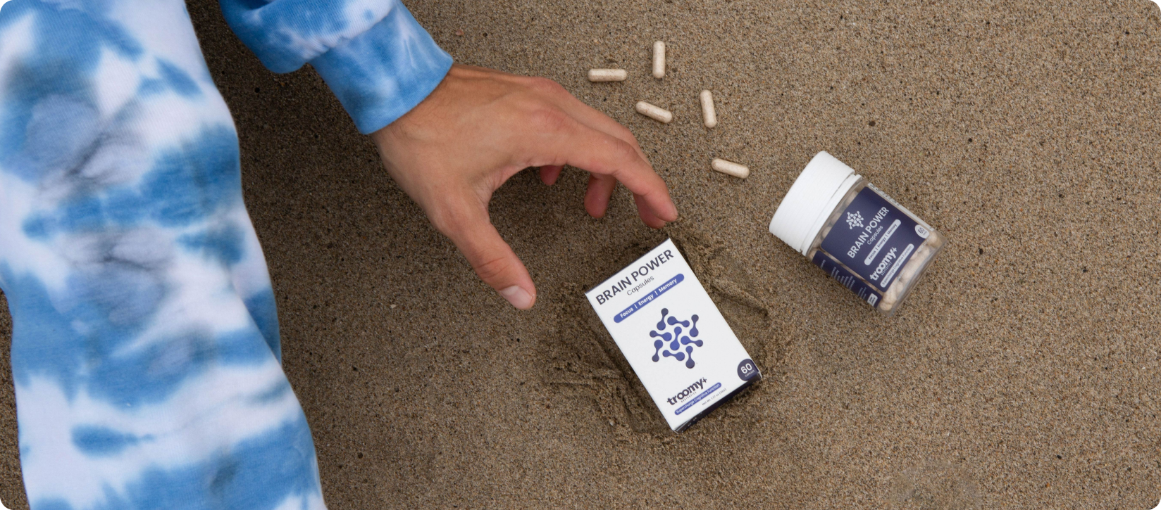 Lion's Mane Mushroom - L-Theanine Supplement - Combining supplements for daily wellness with natural ingredients - Troomy Nootropics in Whittier, CA - Los Angeles County California - Man reaching for brain power capsules on the beach