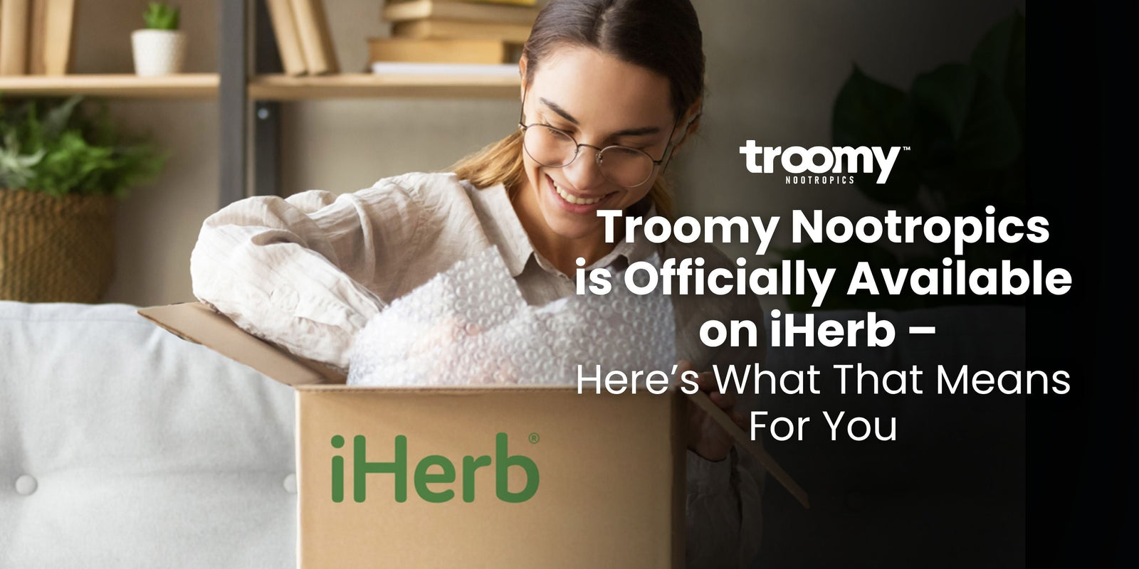 woman smiling opening a cardboard box that says "iHerb" in green text