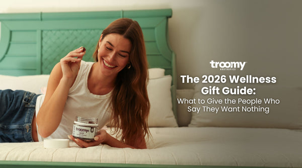 Woman smiling eating reishi mushroom gummies on a bed | Troomy blog: The 2026 Wellness Gift Guide: What to Give the People Who Say They Want Nothing