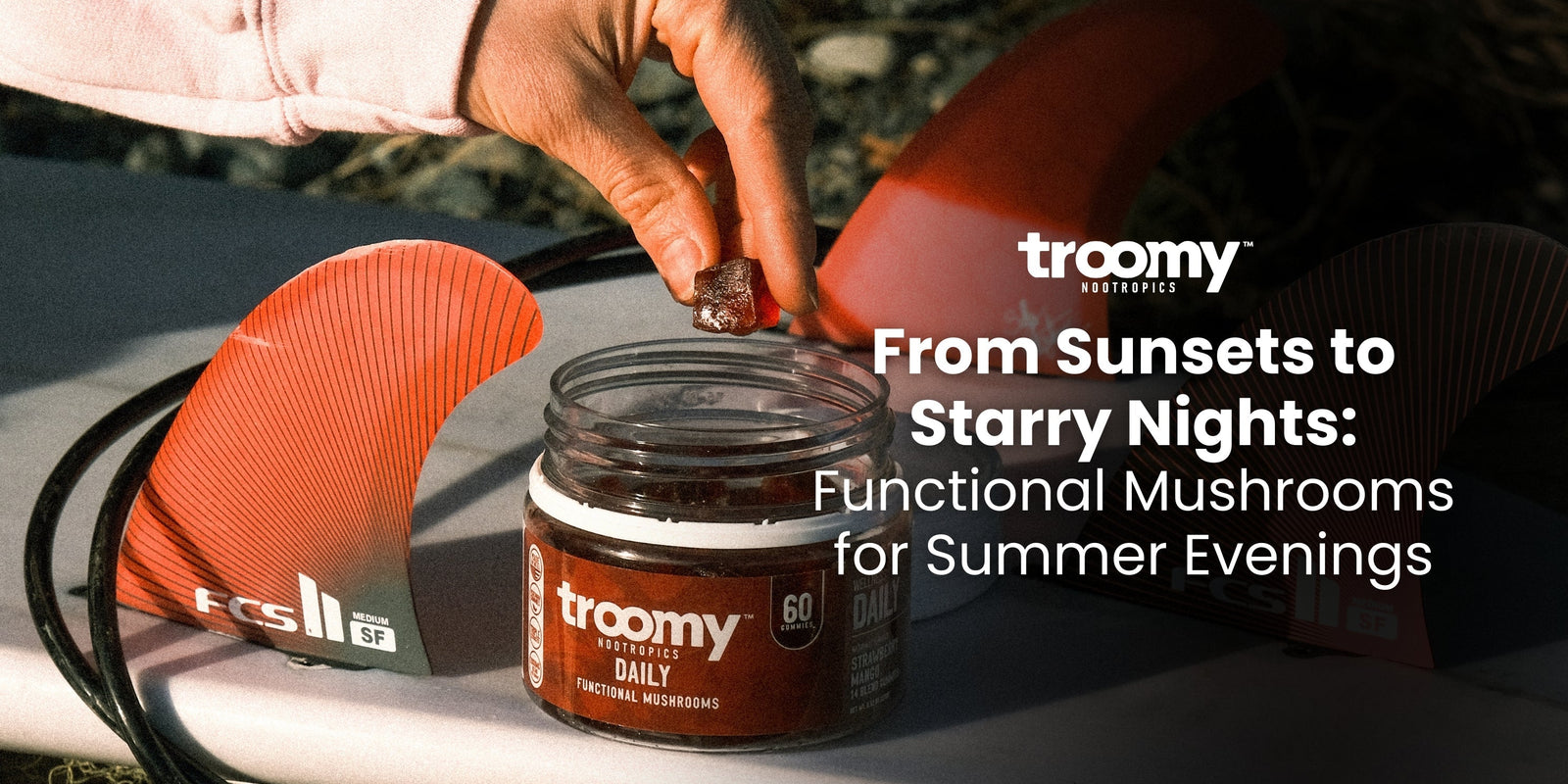 woman reaching into mushroom gummy jar resting on a surfboard at golden hour 