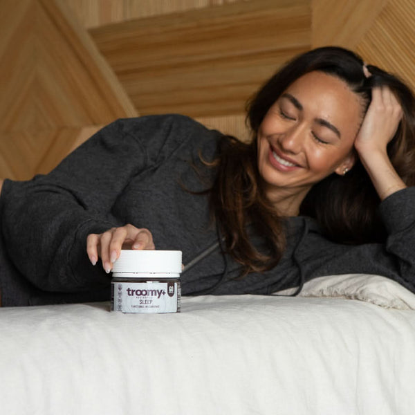 Sleep - Reishi and Melatonin - Black Raspberry - Bedtime Routine- Smiling Woman in Pajamas Holding Gummy - Troomy Nootropics in Whittier, CA